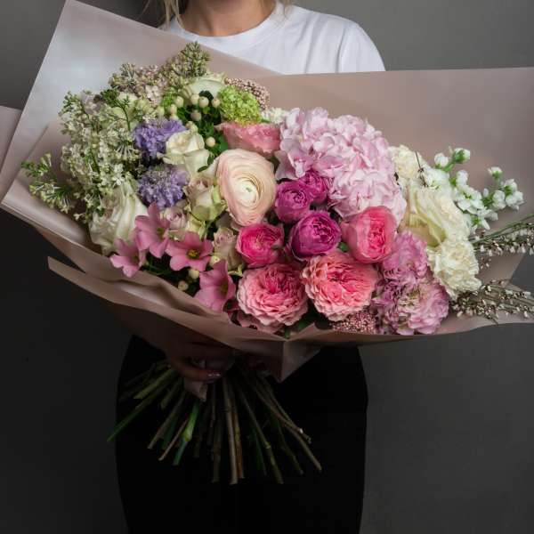 Large pastel bouquet with pink, white, and lavender flowers wrapped in blush paper