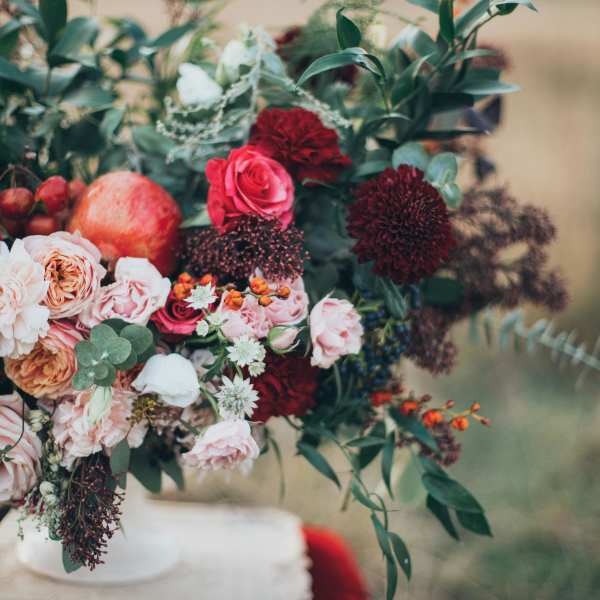 Bouquet of pink and burgundy flowers with greenery in a white vase