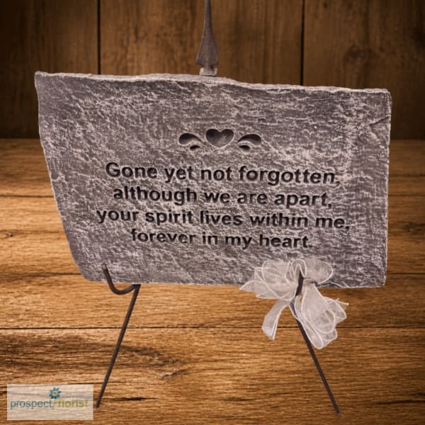 Memorial stone plaque on a metal stand with a white ribbon bow