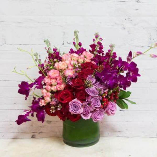 Bouquet of red, pink, and purple roses in a green vase