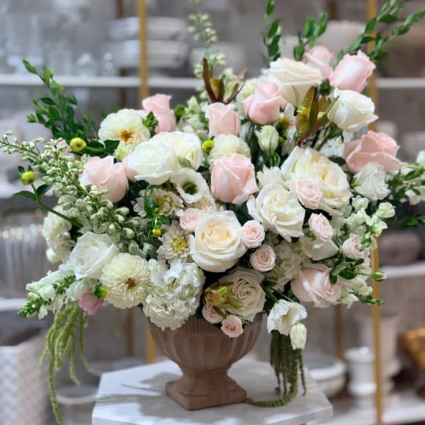 Large pastel rose arrangement in a brown urn vase