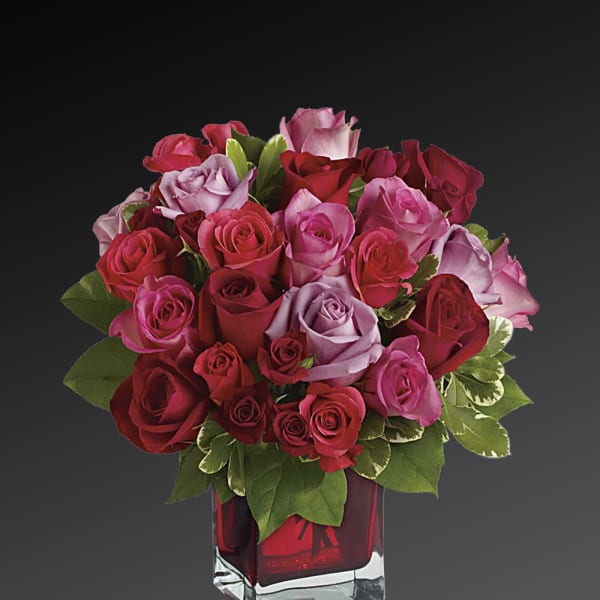 Bouquet of red, pink, and lavender roses in a red glass vase
