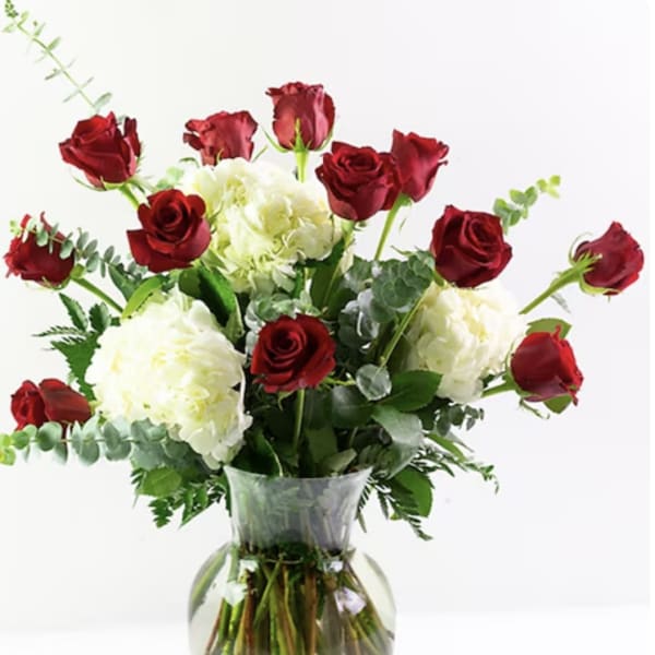 Red roses and white hydrangeas in a clear glass vase