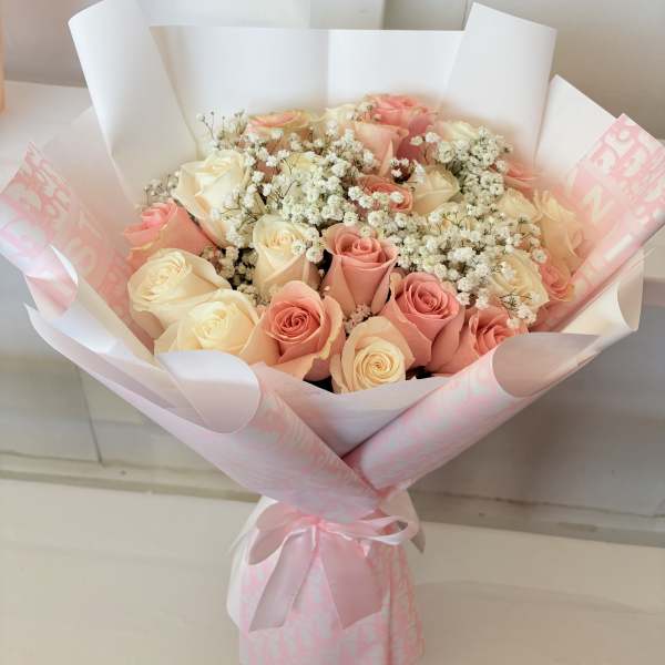 Bouquet of pink and cream roses with baby's breath in pink wrapping