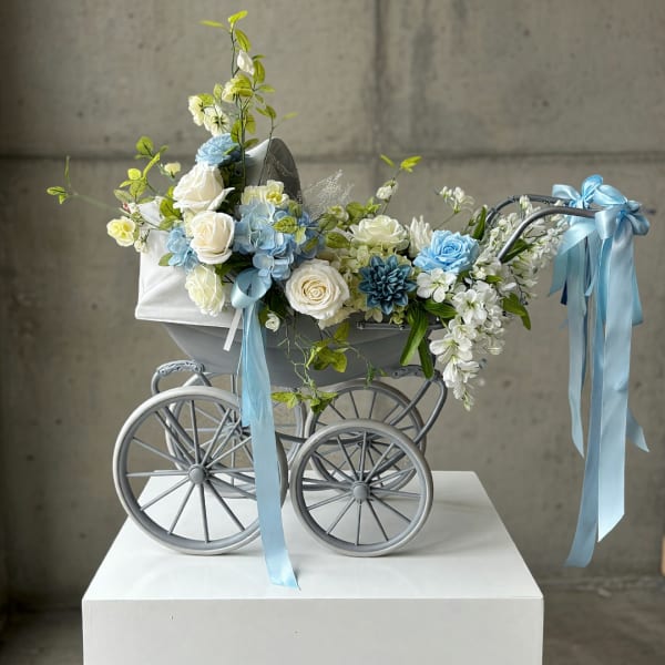 Blue and white floral arrangement in a decorative baby carriage