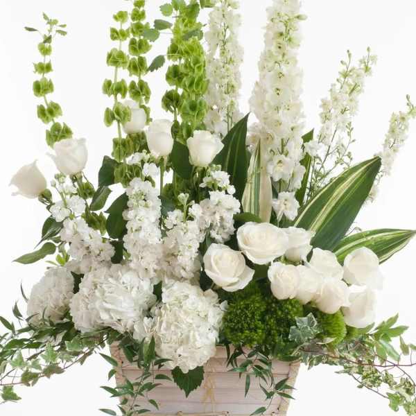 White floral arrangement in a pale basket with tall green and white spikes