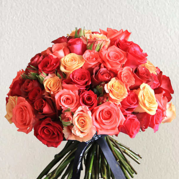 Bouquet of red, pink, and peach roses tied with a dark ribbon