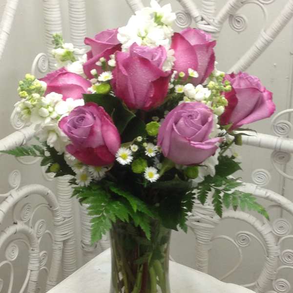 Pink and lavender roses arranged in a clear glass vase with white filler flowers.