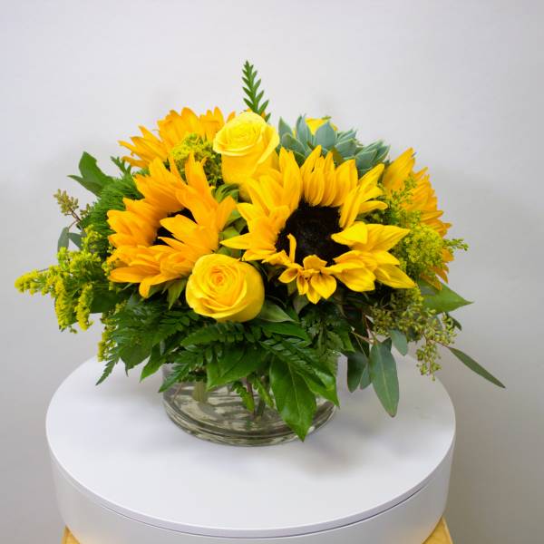 Yellow sunflower and rose arrangement in a clear glass vase