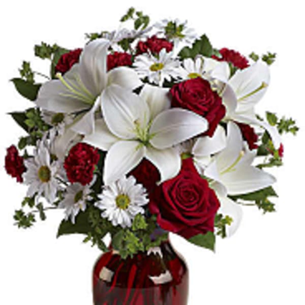 Bouquet of red roses, white lilies, and daisies in a red glass vase