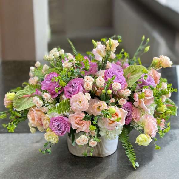 Mixed pink and peach floral arrangement in a white vase