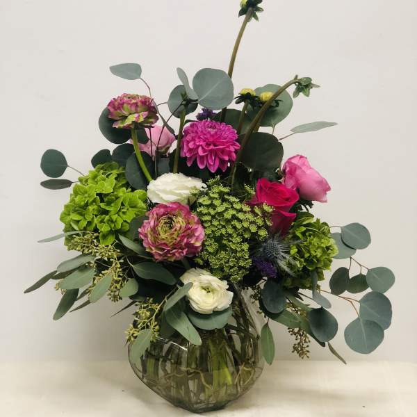 Mixed pink and white flowers in a round glass vase