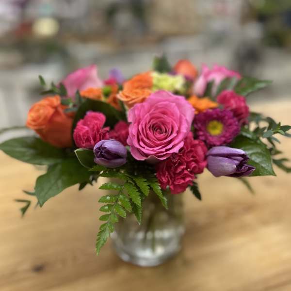 Colorful bouquet of roses, tulips, and carnations in a glass vase