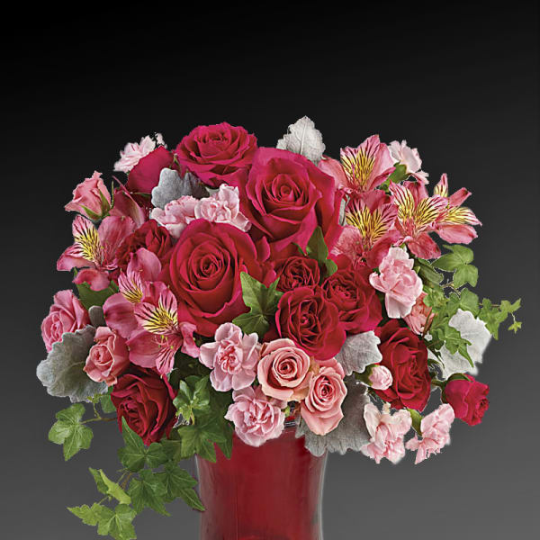 Pink and red rose bouquet in a red glass vase