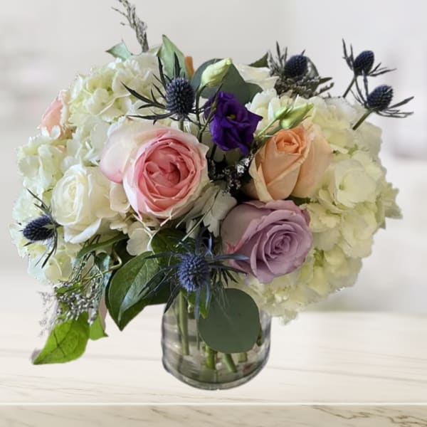 Bouquet of pastel roses and white hydrangeas in a glass vase