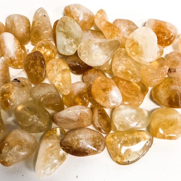 Pile of polished amber-colored stones on a white surface