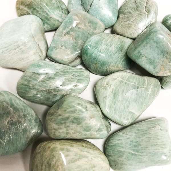 Polished green and white stones arranged on a white surface