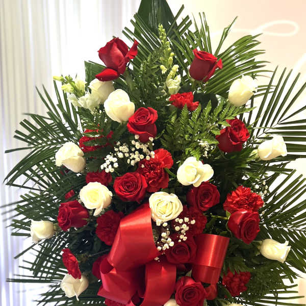 Standing floral spray of red and white roses with a red ribbon