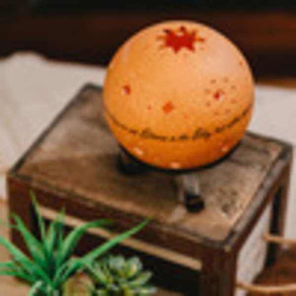 Orange decorative sphere on a wooden box with small plants nearby