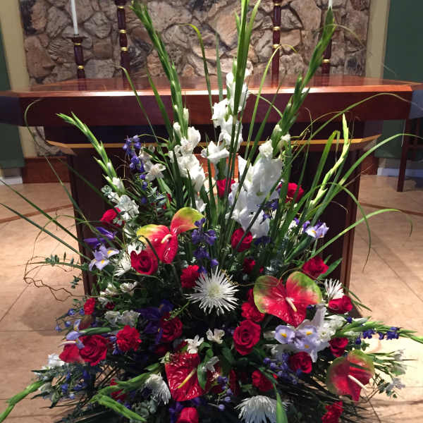 Large floral arrangement with red roses, white gladiolus, and anthuriums