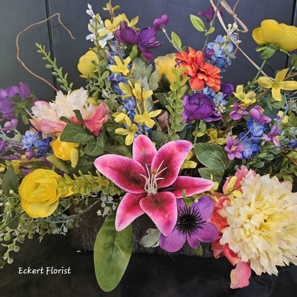 Colorful floral arrangement with lilies, daisies, and mixed blooms in a low container