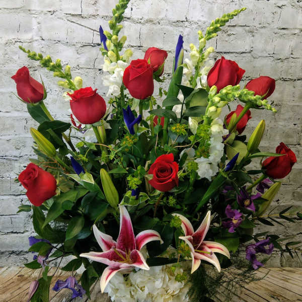 Large bouquet of red roses, white lilies, and purple flowers in a glass vase