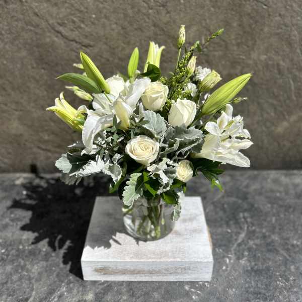 White roses and lilies arranged in a clear glass vase