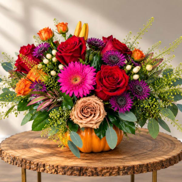 Mixed bouquet in a pumpkin vase with red, orange, and purple flowers
