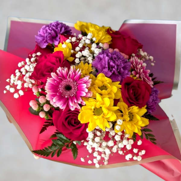 Bouquet of pink, yellow, and purple flowers wrapped in bright paper