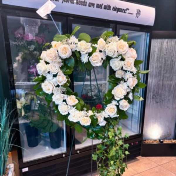 Heart-shaped white rose wreath on a standing easel with trailing ivy