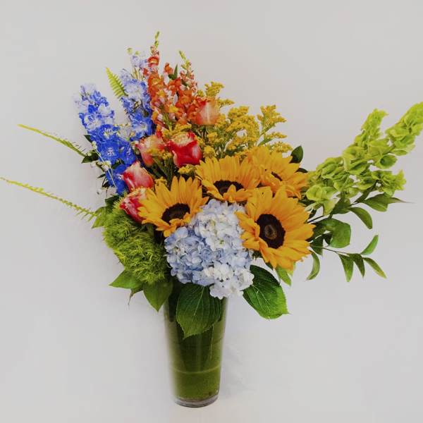 Colorful bouquet with sunflowers, hydrangea, and snapdragons in a glass vase