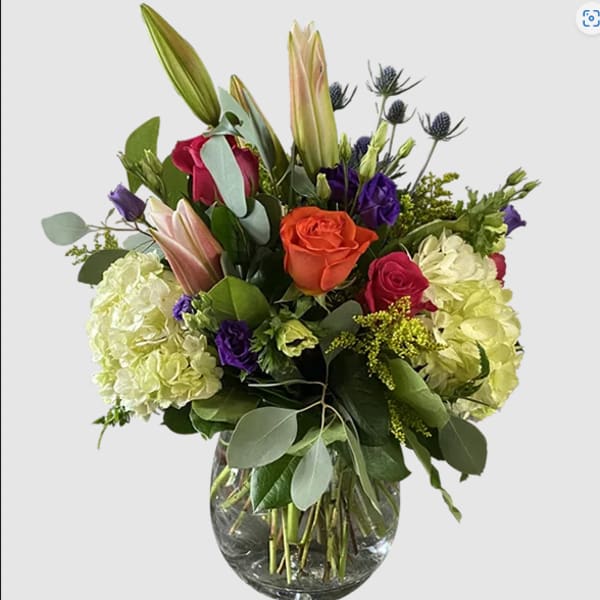 Mixed bouquet of roses, lilies, and hydrangeas in a glass vase
