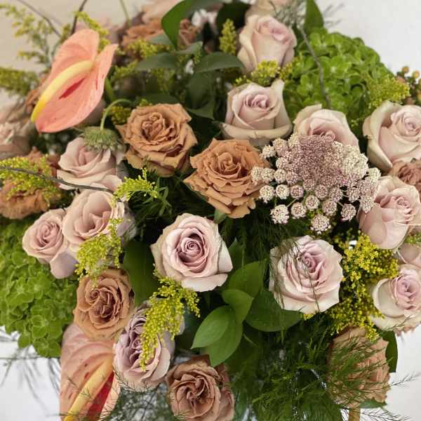 Bouquet of blush and tan roses with pink anthuriums and green filler