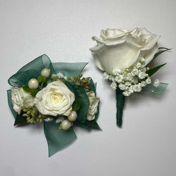 Two white rose boutonnieres with green ribbon and baby's breath