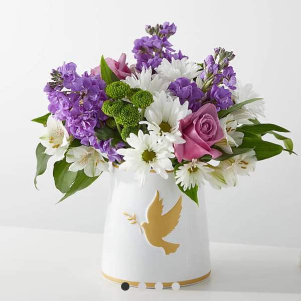 Purple and white bouquet in a white vase with a gold dove design