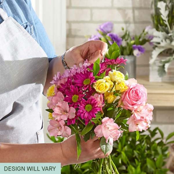 Handheld bouquet of pink, yellow, and purple flowers
