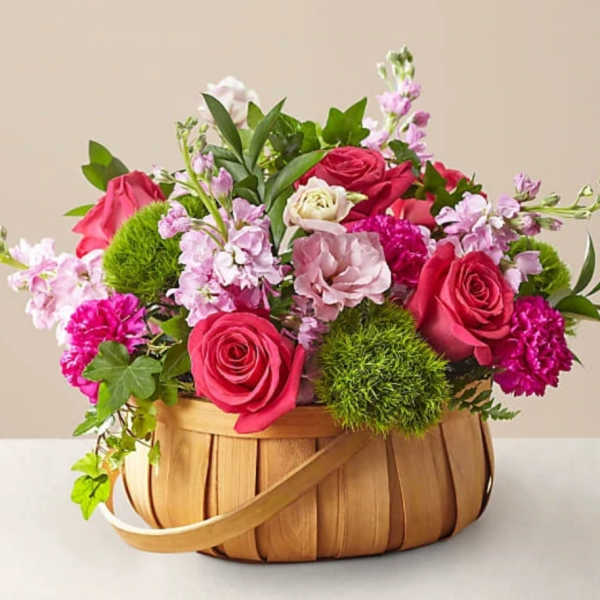 Basket arrangement of pink roses and mixed blooms
