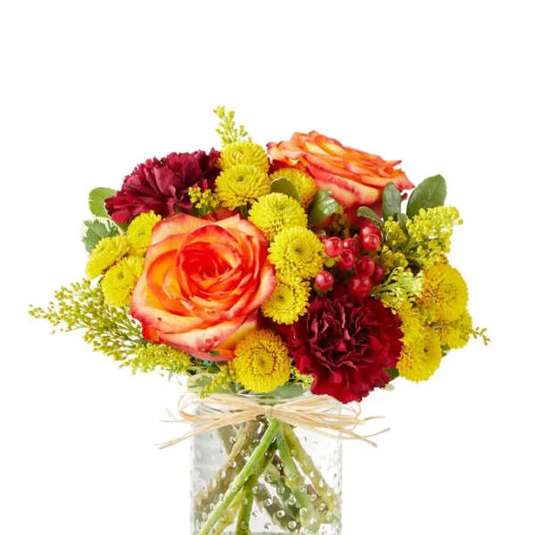 Bouquet of orange roses and yellow and burgundy flowers in a glass vase