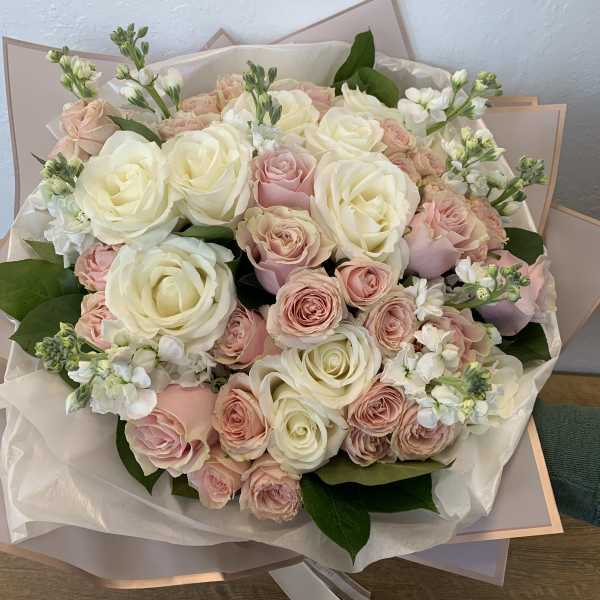 Large bouquet of cream and blush roses with white filler flowers