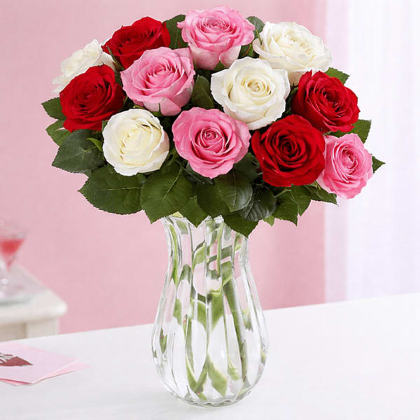 Bouquet of red, pink, and white roses in a clear glass vase
