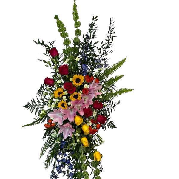Tall standing floral spray with roses, lilies, sunflowers, and blue accents