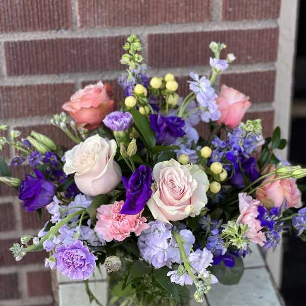 Mixed pink, purple, and lavender flowers in a glass vase