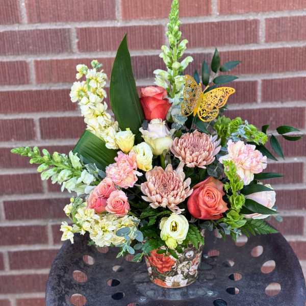 Mixed bouquet in a floral-patterned container with pink and cream flowers