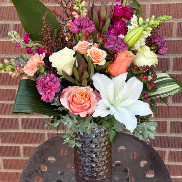 Mixed bouquet in a textured vase with roses, lilies, and carnations