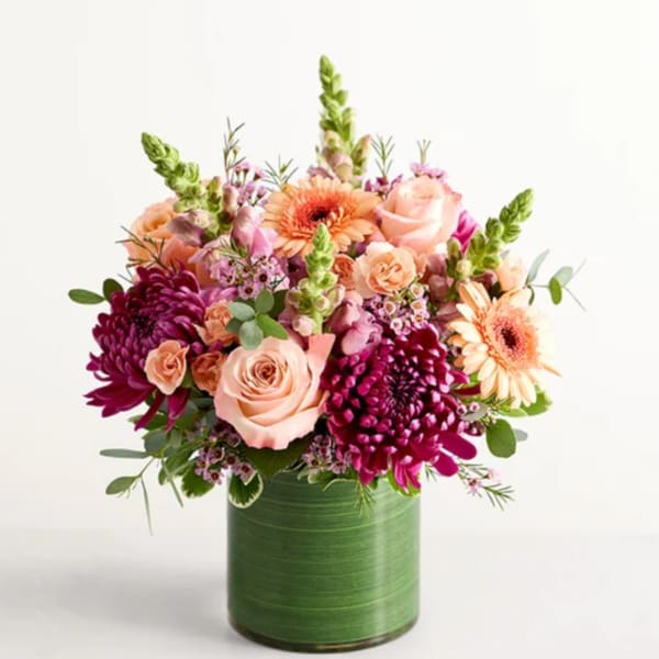 Pink and peach flowers arranged in a green vase