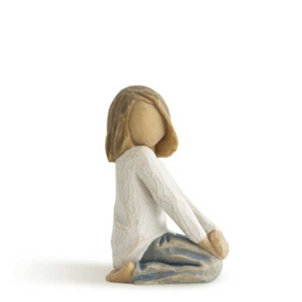 Wooden figurine of a seated girl in a white top and blue pants