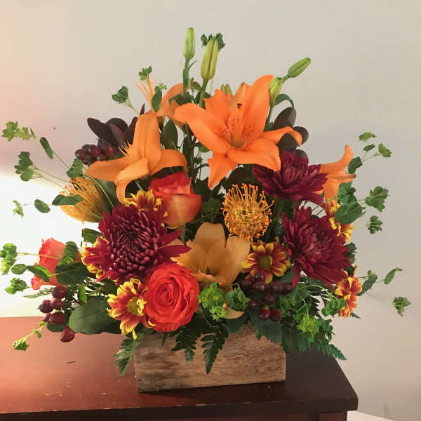 Orange lilies and red chrysanthemums in a wooden box arrangement