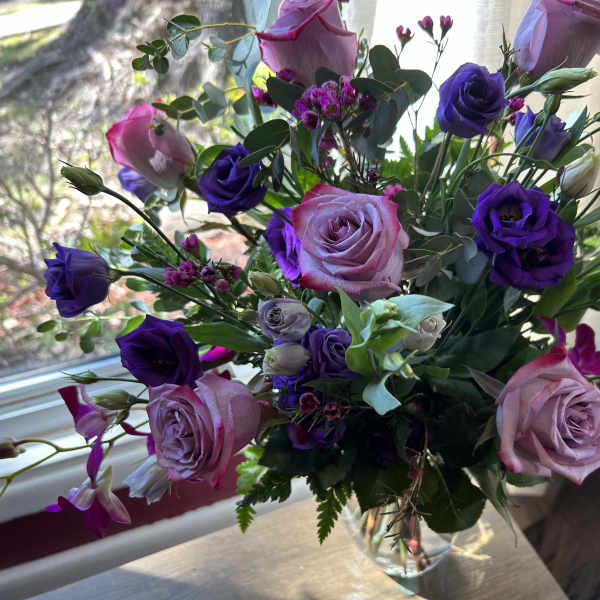 Bouquet of pink and purple roses in a clear glass vase