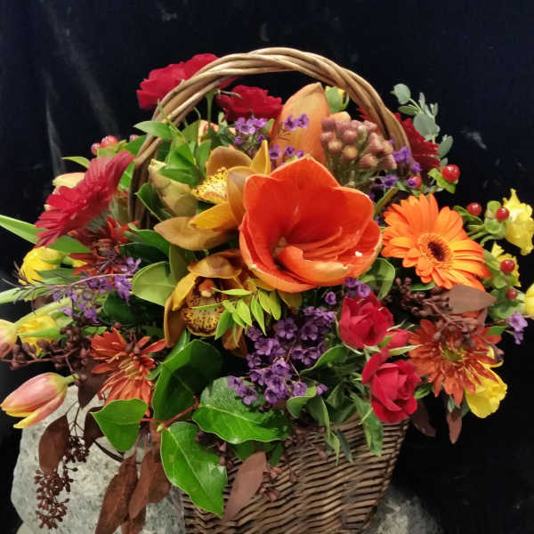 Basket arrangement with orange, red, and purple flowers