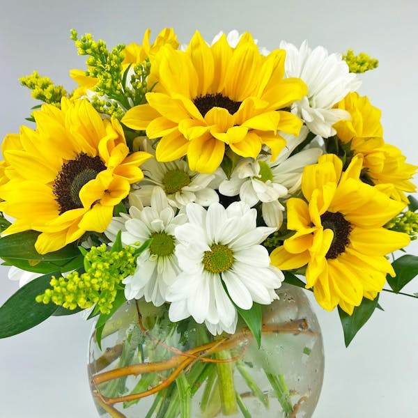 Bouquet of yellow sunflowers and white daisies in a round glass vase